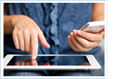 woman working on a tablet while holding a mobile phone